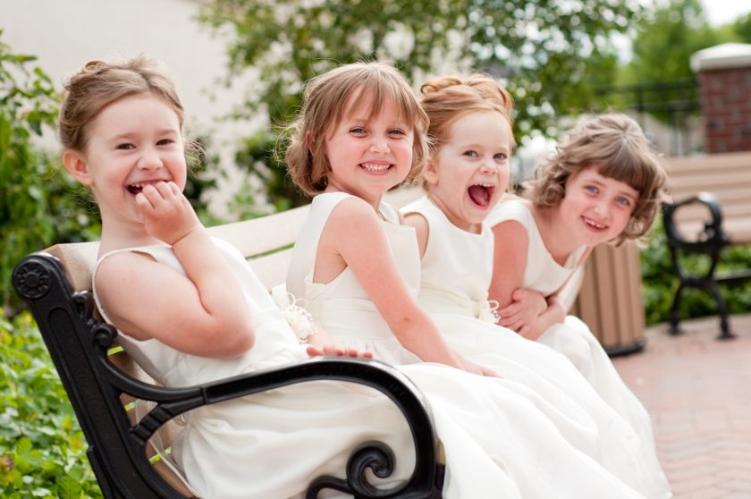 Four Happy Little Flower Girls Laughing Together in Formal Dresses